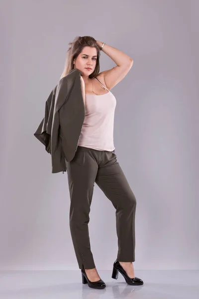 Retrato de un modelo femenino de talla grande posando en traje de broun sobre fondo gris . —  Fotos de Stock