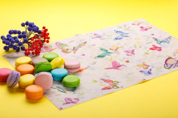 Galletas coloridas de macarrones franceses en la servilleta sobre fondo amarillo — Foto de Stock