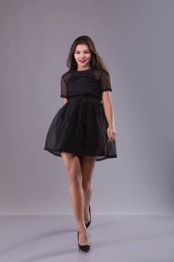 siyah elbiseli yürüyen esmer kadın görünümünü iletmek. hareket gülümseyen kız güzel. frontview bir insan. gri arka plan üzerinde. Görünüm insanlar koleksiyonu.