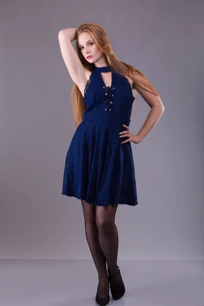 Portret van een plus grootte vrouwelijke roodharige model poseren in blauwe jurk over de grijze achtergrond. — Stockfoto