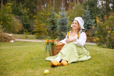 peasant woman with a basket seating on the lawn clipart