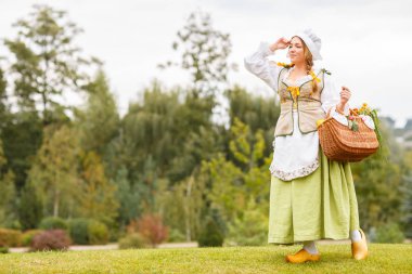 Genç güzel köylü kadın çanta veya sepet ayçiçeği bir buket ile çok uzak görünüyor