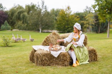 köylü kadın saman üzerinde oturur. Piknik için yürüyüş