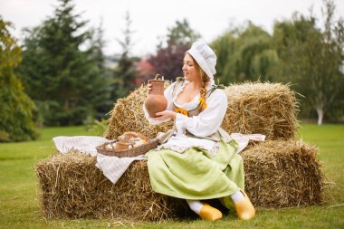 Köylü kadın saman üzerinde oturur ve süt dökülen