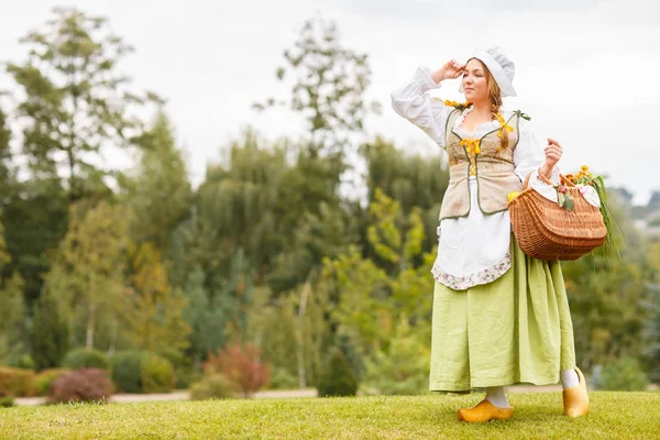 Genç güzel köylü kadın çanta veya sepet ayçiçeği bir buket ile çok uzak görünüyor