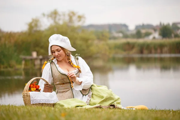 En bonde kvinna med en korg sitter vid floden — Stockfoto