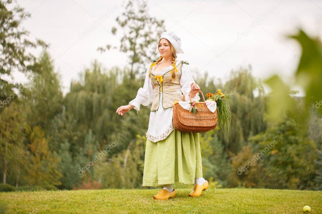 a peasant woman walks with a basket in park