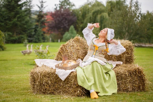 köylü kadın SIPs saman üzerinde