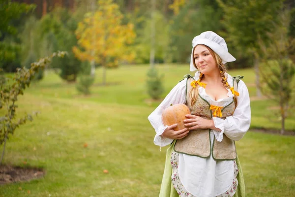 Bonde kvinna med en pumpa i bakgrunden av en äng — Stockfoto