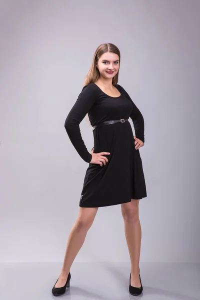Portréja egy plusz méretű női modellt jelentő fekete ruha felső szürke háttér. — Stock Fotó