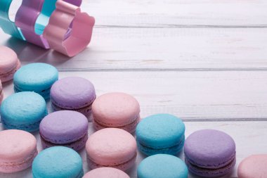Beyaz ahşap arka plan üzerinde renkli tatlı macaroons. Metin için yer