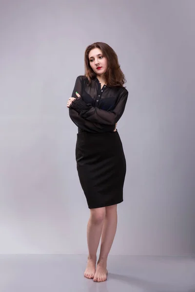 Vackra barfota brunett kvinna klädd i svarta kläder på grå bakgrund — Stockfoto