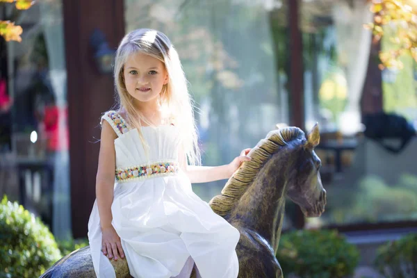 Retrato de linda menina loira em um cavalo de ferro, verão — Fotografia de Stock