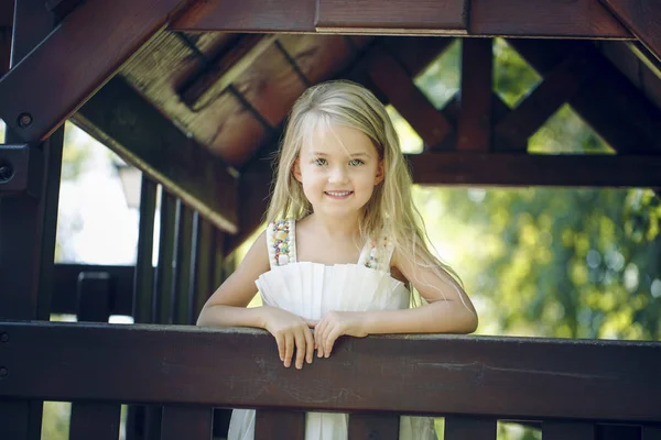 Liten flicka på lekplatsen. trähus. solig dag. Sommartid — Stockfoto