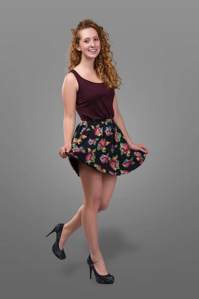 Bonito plus tamanho jovem ruiva e encaracolado menina vestindo saia curta com impressão floral sobre fundo cinza. Mais o tamanho — Fotografia de Stock