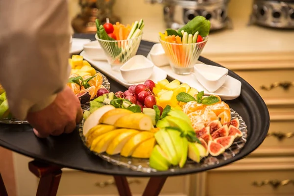 Garçom transportando bandeja com pratos com frutas e legumes em algum evento festivo — Fotografia de Stock