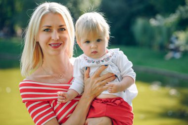 Güzel genç anne ve kızını sarılma ve gülümseyerek kameraya bakarak portre