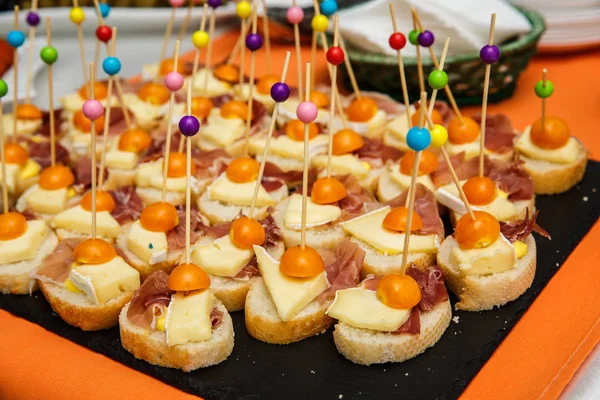 Assorted canapes on table closeup. Selection of tasty bruschetta on toasted baguette with prosciuto cheese tomato — Stockfoto