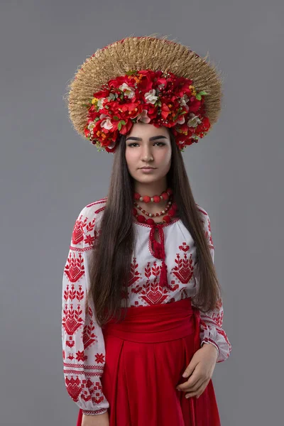 Mujer atractiva lleva vestido nacional ucraniano o bordado y corona de flores y espigas sobre un fondo gris — Foto de Stock