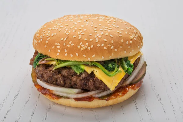 Hamburger with meat cutlet, pickle, onion, cheese, spinach and spicy sauce — Stock Photo, Image