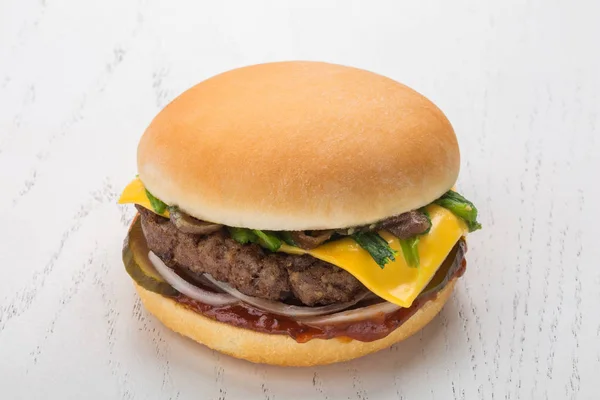 Cheeseburger with meat cutlet and salted cucumber, onion, spinach, caramelized onion, cheese and spicy sauce — Stock Photo, Image