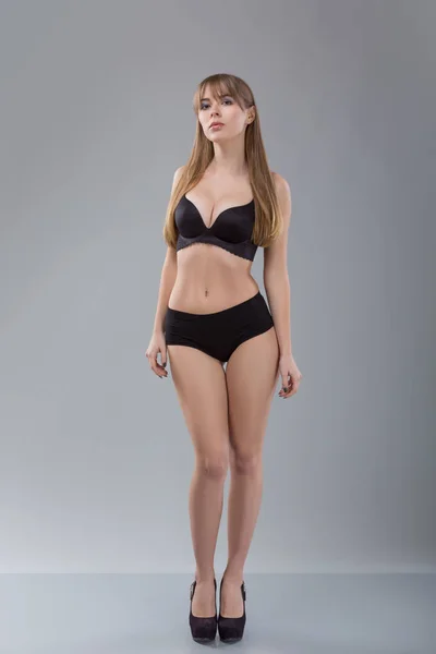 Gri arka plan üzerinde siyah Bikini kusursuz kadın. Kız ince tonda gövde ile fotoğraf. Güzellik ve vücut bakım kavramı