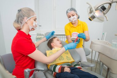 diş hekimi ile küçük çocuk nasıl bir yapay çene kukla üzerinde bir diş fırçası ile dişleri temizlemek için gösterilen kalfa