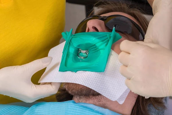 Пацієнт отримує стоматологічне лікування в стоматологічному кабінеті із захистом від каучукової греблі та затискачем розумної матриці, запобігаючи забрудненню слини. Стоматологічна допомога, інструменти та концепція технології . — стокове фото