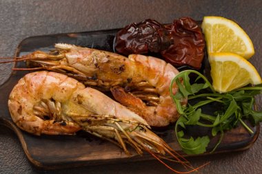Fried kaplan karides ile limon, kurutulmuş domates ve yeşillik veya rukkola koyu ahşap kesme tahtası.