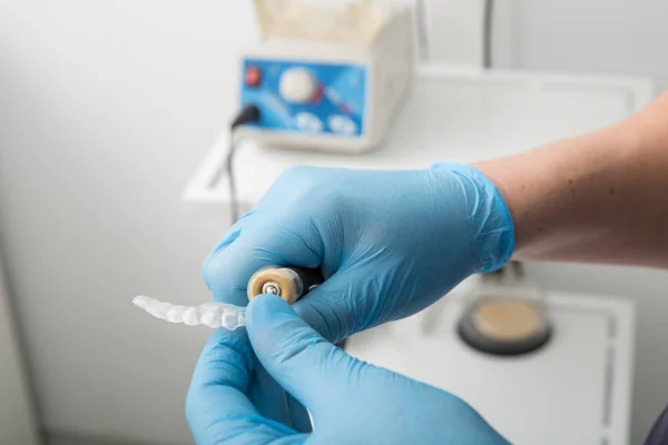 Primer plano en las manos del dentista cubiertas con guantes de látex formando protector bucal con equipo de archivo — Foto de Stock