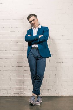 Mavi ceket ve beyaz tuğla duvar tarafından açık poz gözlük yakışıklı adam. Erkek güzelliği, moda. İş tarzı.