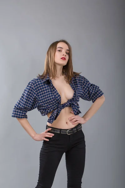 Retrato de chica con estilo en una camisa de vaquero sin sujetador sobre un fondo gris —  Fotos de Stock