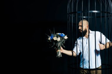 bir buket çiçek ile uzatarak sakallı adam. Acımasız adam içinde belgili tanımlık kafes siyah arka plan üzerinde