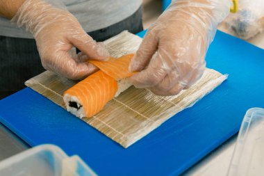 Profesyonel suşi şefi ticari mutfak rulo hazırlanıyor. Cook somon roll üzerine koyar. Japon mutfağı yemek tarifleri