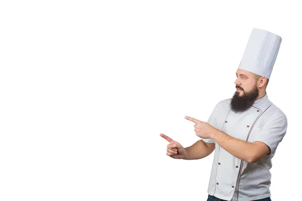 Cozinheiro barbudo chef apontando com os dedos isolados no fundo branco, espaço cópia no lado . — Fotografia de Stock