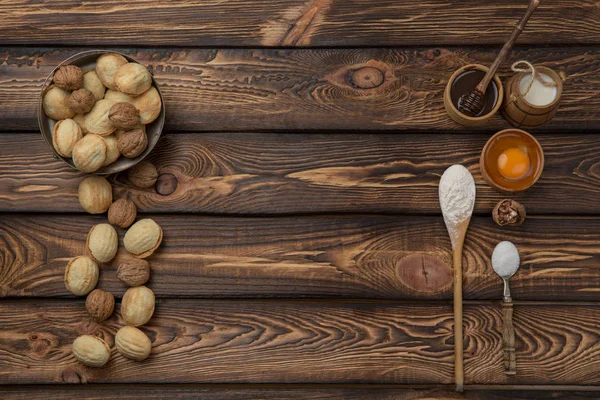 Voedsel achtergrond. Bakken ingrediënten meel, eieren, noten, suiker, gedroogde vruchten op houten tafel. bovenaanzicht. Kopiëren van ruimte. — Stockfoto