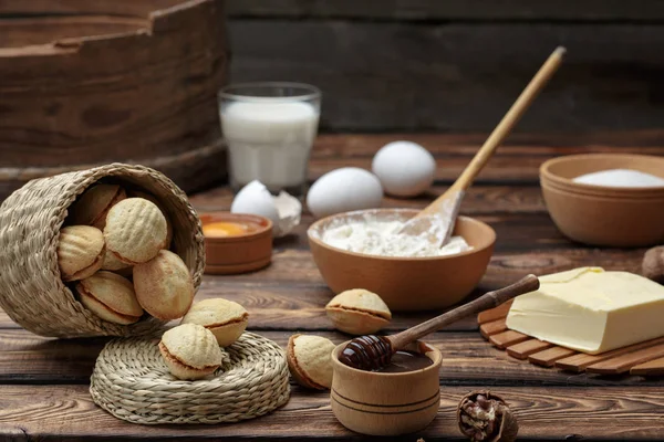 Heerlijke walnoot vormige zandkoekkoekjes broodje gevuld met zoete gecondenseerde melk en gehakte pistachenootjes op bruin klei schotel. op oude houten achtergrond, weergave van bovenaf, close-up — Stockfoto