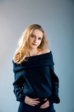 Gri arka plan üzerinde siyah kazak çıplak omuz ile poz çekici genç hanım portresi