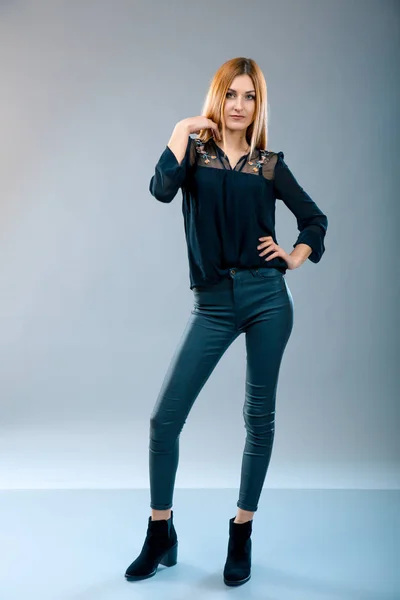 灰色の背景に黒の t シャツとジーンズを着て美しい赤毛のファッションモデル. — ストック写真