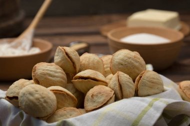 lezzetli ceviz şeklinde kurabiye sandviç kurabiye tatlı yoğunlaştırılmış süt ile dolu ve kahverengi Kil çanak üzerinde Antep fıstığı doğranmış. Yukarıdaki eski ahşap arka plan üzerinde göster