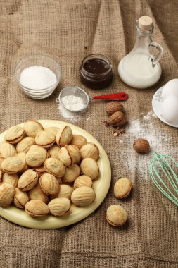 şekilli kurabiye sandviç kurabiye tatlı yoğunlaştırılmış süt ile dolu ve kıyılmış fındık çul arka plan, yukarıdan görünüm, yakın çekim lezzetli ceviz