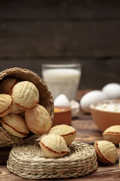 Delicious walnut shaped shortbread sandwich cookies filled with sweet condensed milk and chopped nuts on old wooden background, view from above, close-up — Stock Photo, Image