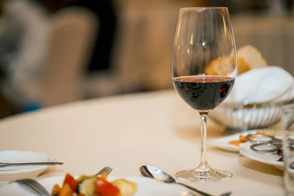 Glas rode wijn en diner op een gedekte tafel. een restaurant. wachten op de vergadering — Stockfoto