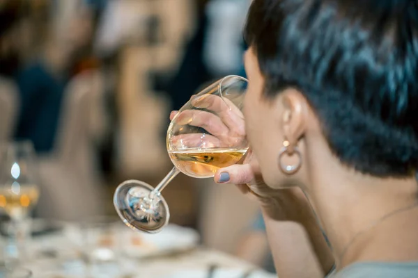 Женщина пьет белое вино на официальном приеме в ресторане — стоковое фото