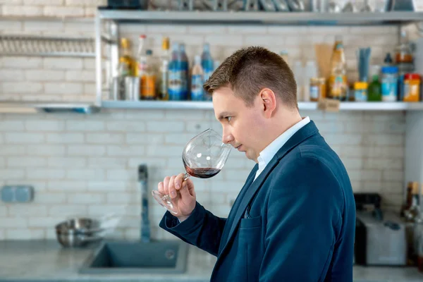Enólogo ou sommelier farejadores de vinho tinto em um copo no interior da cozinha — Fotografia de Stock