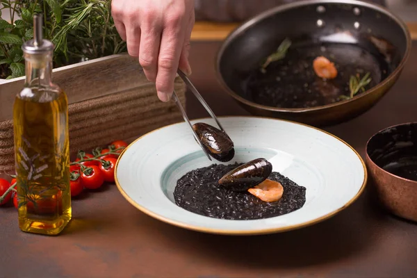 Şef deniz ürünleri, midye hazırlar, karides yemek beyaz bir tabak içinde koyar.