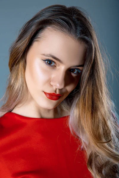 Ritratto di bella giovane donna con labbra rosse e vestito rosso su sfondo grigio blu — Foto Stock