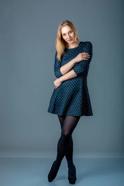 Hermosa mujer caucásica de talla grande en vestido de lunares azul oscuro. Retrato de larga duración de atractiva joven hembra posando sobre fondo gris . — Foto de Stock