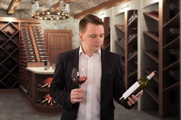 Enólogo inspecionando a qualidade do vinho tinto, de pé perto frascos racks em abóbada adega — Fotografia de Stock