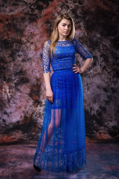 Mulher loira elegante no vestido espumante noite azul está posando em mármore colorido fundo — Fotografia de Stock